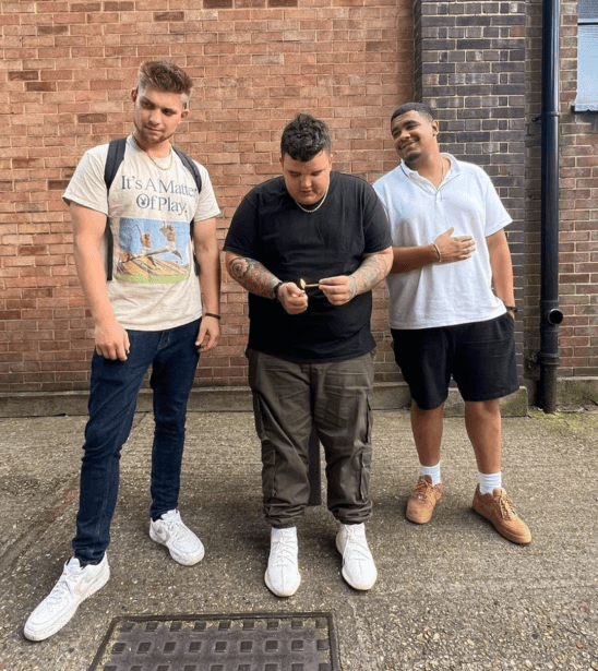 AJ Deleon posing with friends in front of brick wall